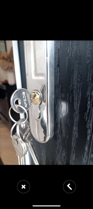 Close-up of a door lock with a key inserted, attached to a wooden door.