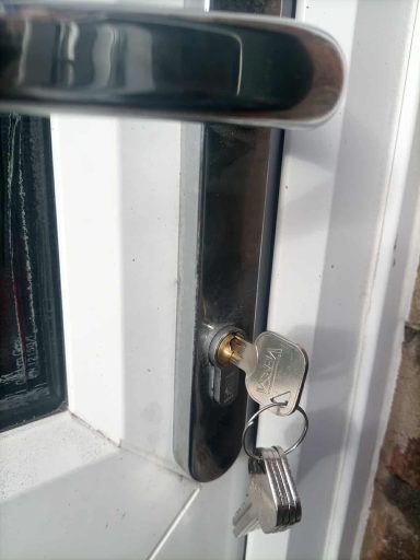 Close-up of a door lock with a key inserted and the door handle visible.