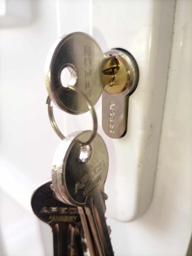 A set of keys inserted into a door lock with a shiny metal finish.